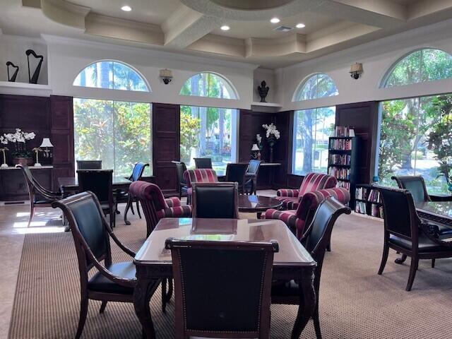 dining space with beam ceiling, coffered ceiling, a high ceiling, carpet flooring, and crown molding