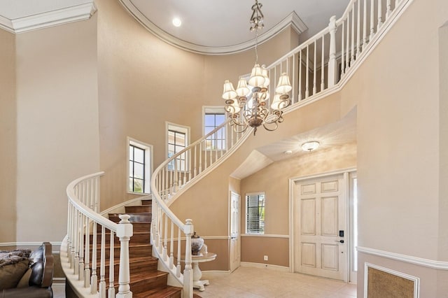 entrance foyer featuring baseboards, stairway, ornamental molding, an inviting chandelier, and a towering ceiling