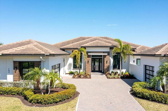 view of front facade with a tiled roof, decorative driveway, and stucco siding