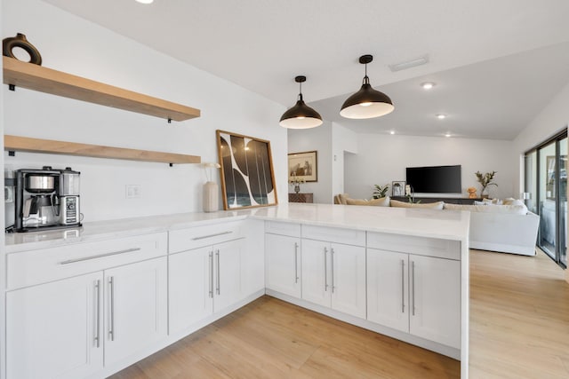 kitchen featuring light wood finished floors, a peninsula, vaulted ceiling, light countertops, and open shelves