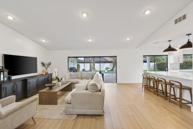 living area with recessed lighting, visible vents, vaulted ceiling, and light wood finished floors