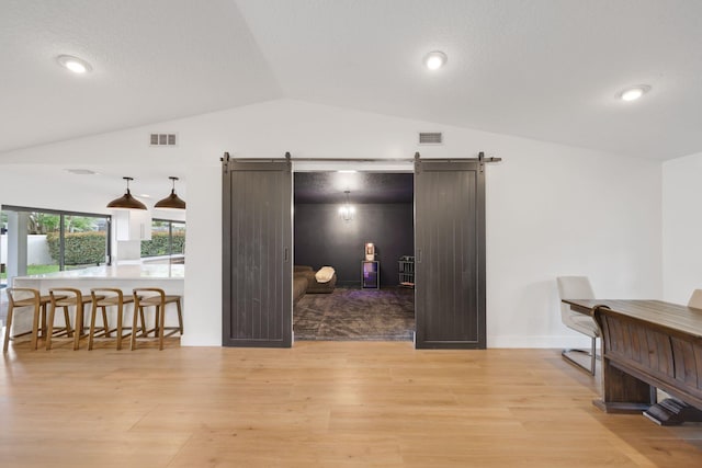 office with lofted ceiling, a barn door, and visible vents