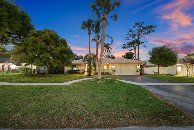 ranch-style home featuring a yard, driveway, an attached garage, and fence