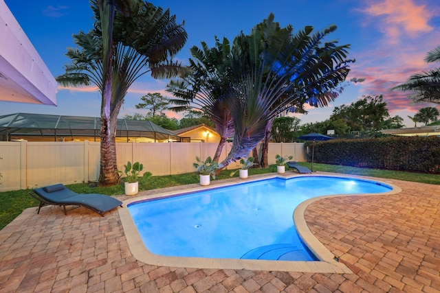 pool at dusk with a patio area, a fenced backyard, and a fenced in pool