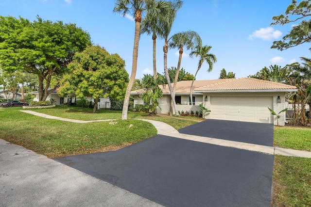 view of front facade featuring an attached garage, driveway, a tiled roof, and a front yard