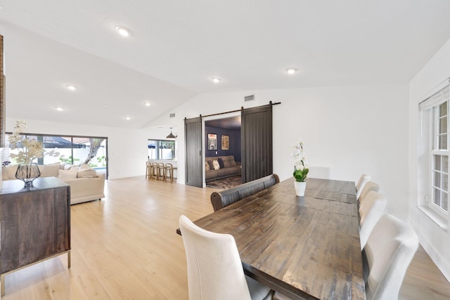 dining space with light wood-type flooring, a barn door, vaulted ceiling, and recessed lighting