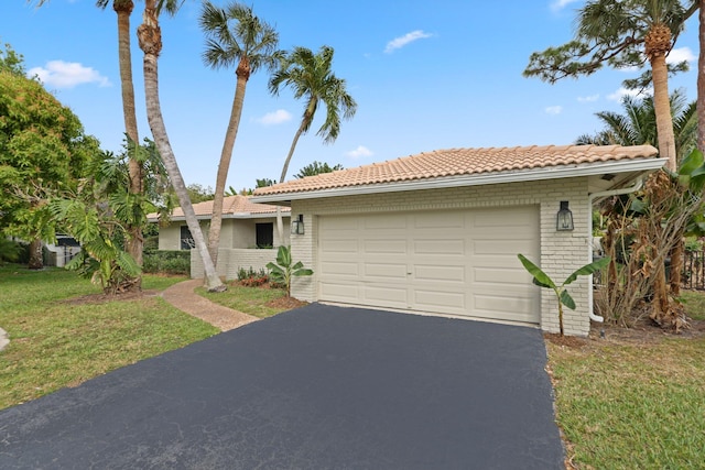 ranch-style home featuring a garage, brick siding, a tile roof, driveway, and a front yard