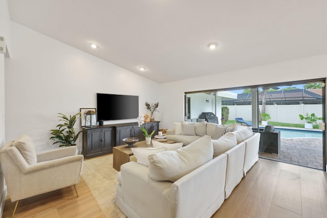 living room featuring vaulted ceiling, light wood-type flooring, a sunroom, and recessed lighting