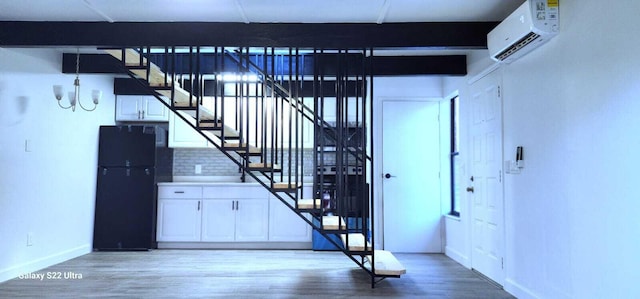 staircase featuring a chandelier, a wall unit AC, baseboards, and wood finished floors