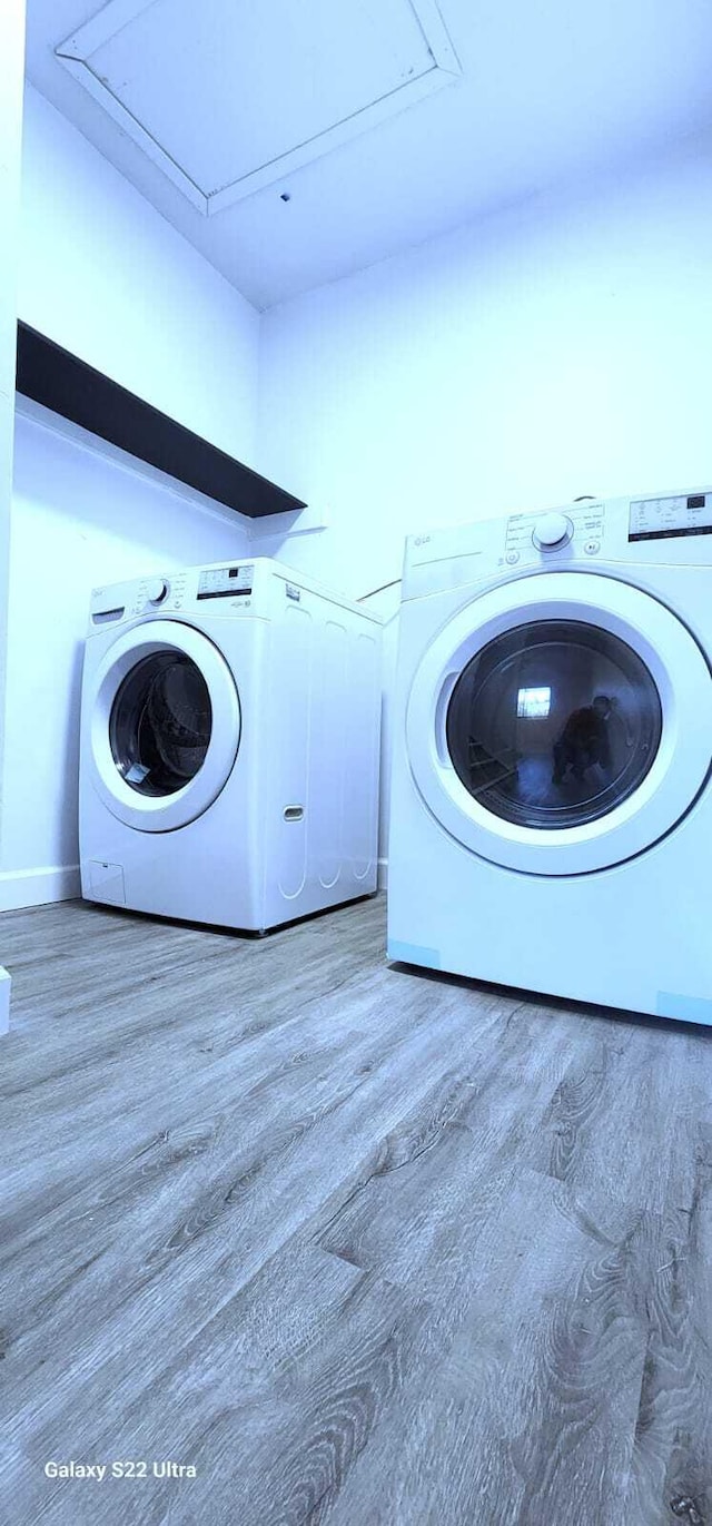 clothes washing area with laundry area, baseboards, wood finished floors, and independent washer and dryer