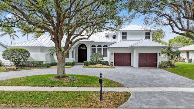 view of front of home with decorative driveway, a standing seam roof, metal roof, and a garage