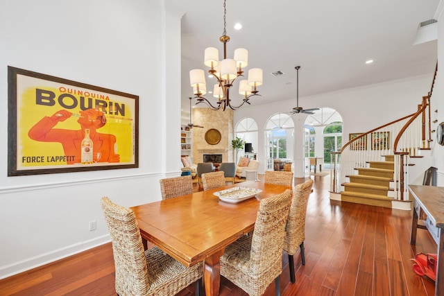 dining area with dark wood-type flooring, visible vents, a fireplace, and stairway