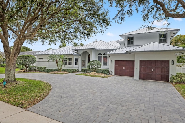 view of front of home featuring metal roof, a garage, decorative driveway, stucco siding, and a standing seam roof