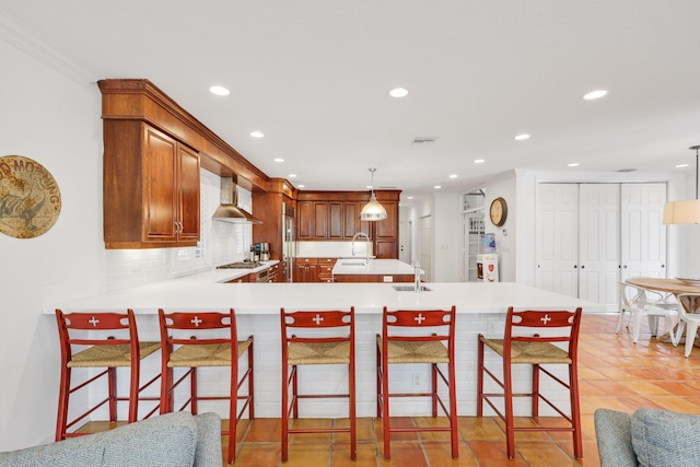 kitchen with tasteful backsplash, light countertops, a sink, and wall chimney exhaust hood