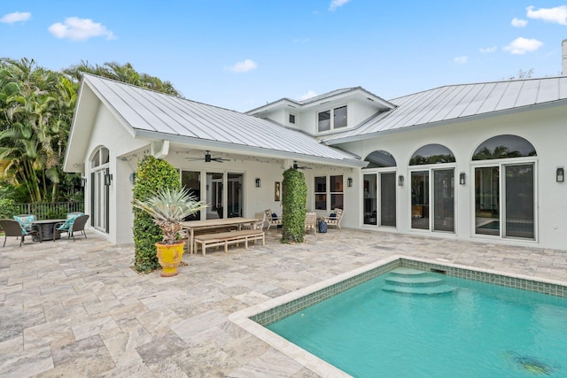 back of property with metal roof, a standing seam roof, a patio area, and a ceiling fan