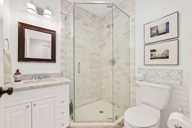 bathroom featuring toilet, a shower stall, and vanity