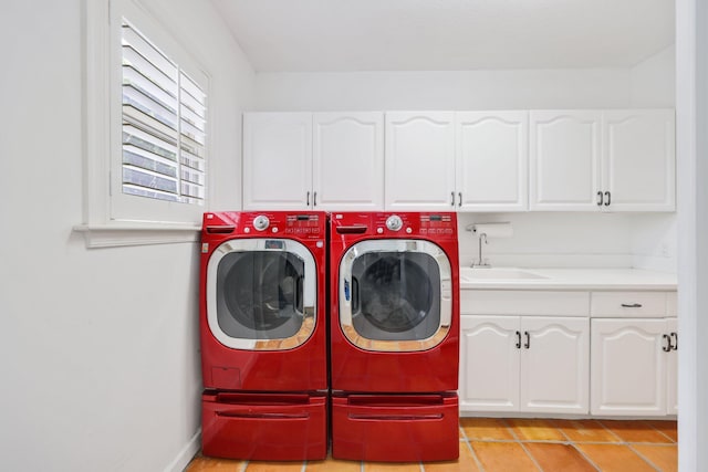 laundry room with cabinet space, baseboards, separate washer and dryer, and a sink