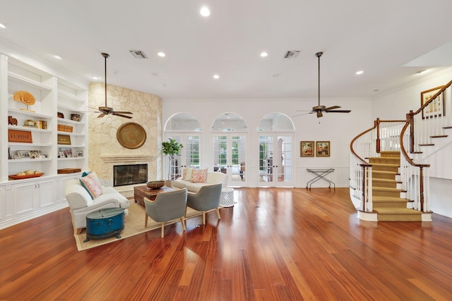 living room with built in shelves, a fireplace, visible vents, french doors, and stairway