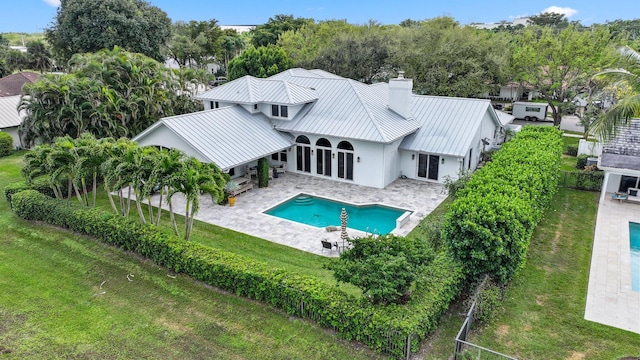 back of house with a patio, a fenced backyard, metal roof, a standing seam roof, and a yard