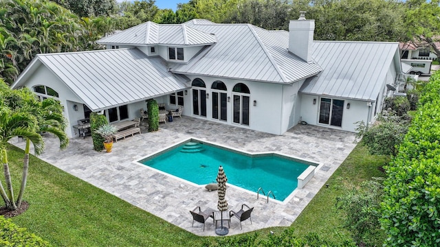 rear view of property featuring metal roof, a standing seam roof, and a patio area