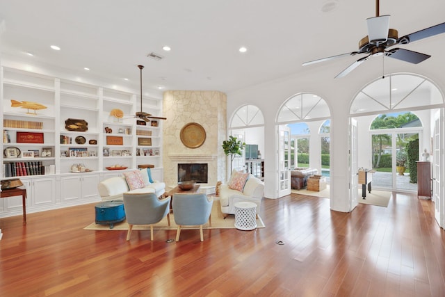 living room with visible vents, a fireplace, light wood finished floors, and ceiling fan