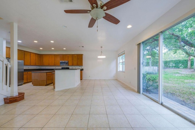 kitchen with dark countertops, a kitchen island, appliances with stainless steel finishes, light tile patterned flooring, and recessed lighting