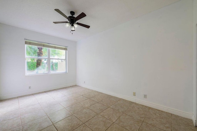 spare room featuring ceiling fan, a textured ceiling, light tile patterned flooring, and baseboards