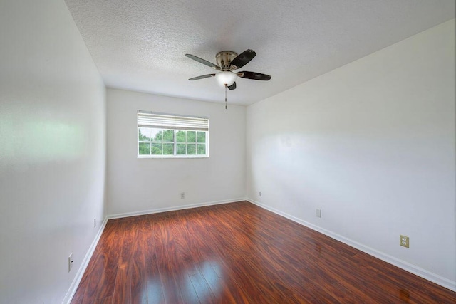 spare room featuring a textured ceiling, ceiling fan, dark wood-type flooring, and baseboards