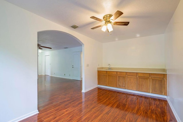 spare room with arched walkways, ceiling fan, a textured ceiling, dark wood-style flooring, and visible vents