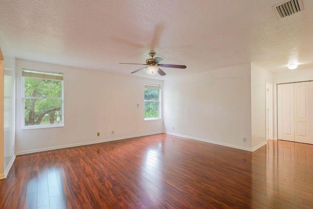 empty room with visible vents, a textured ceiling, baseboards, and hardwood / wood-style flooring