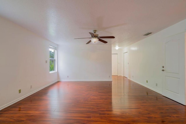 spare room featuring a textured ceiling, wood finished floors, visible vents, and baseboards