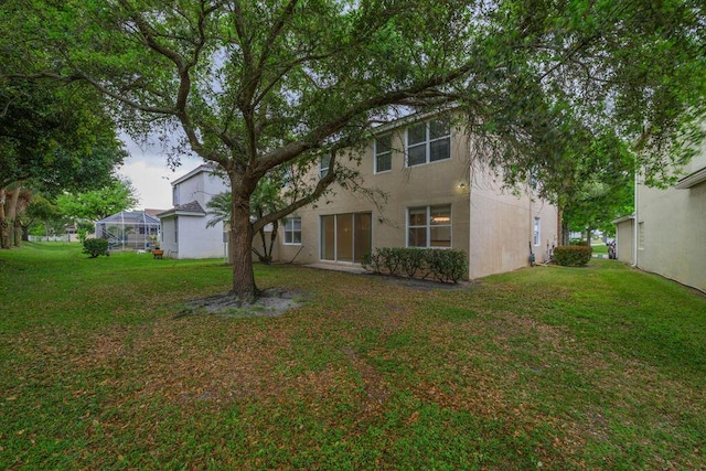 view of front of house with glass enclosure, a front lawn, and stucco siding