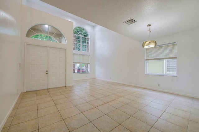 foyer with light tile patterned floors, a textured ceiling, visible vents, and baseboards