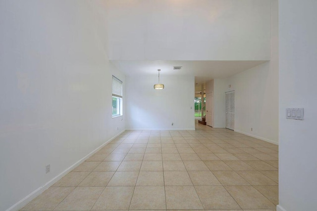 empty room with light tile patterned floors, visible vents, and baseboards