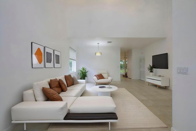 living room featuring visible vents, a high ceiling, and light tile patterned floors