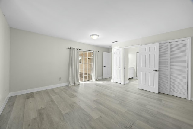 unfurnished bedroom featuring ensuite bathroom, light wood-type flooring, visible vents, and baseboards