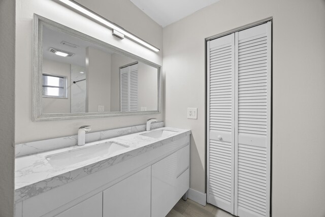 full bath featuring double vanity, a closet, visible vents, and a sink