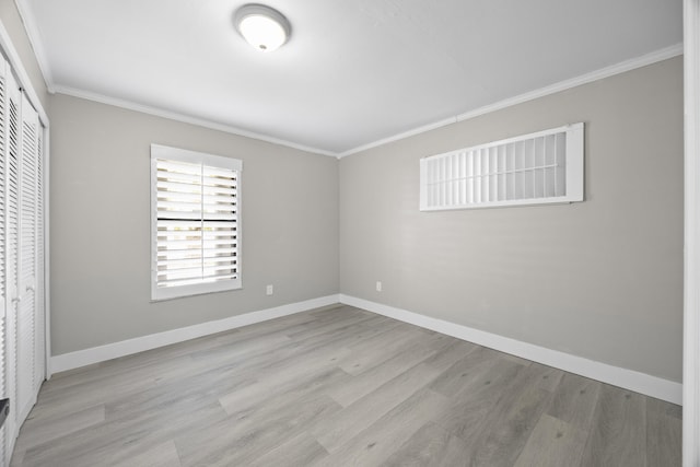 unfurnished bedroom with a closet, baseboards, crown molding, and wood finished floors