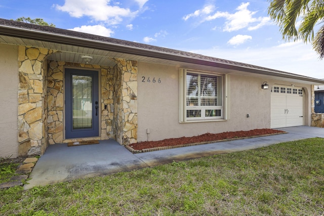 property entrance featuring a garage, stone siding, and stucco siding