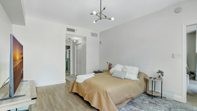 bedroom featuring an inviting chandelier, wood finished floors, visible vents, and baseboards