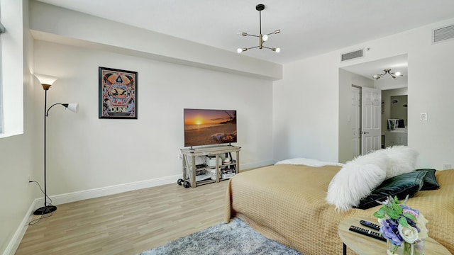 bedroom with visible vents, baseboards, a notable chandelier, and wood finished floors