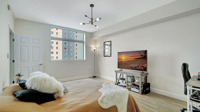 bedroom featuring light wood-type flooring, baseboards, and an inviting chandelier