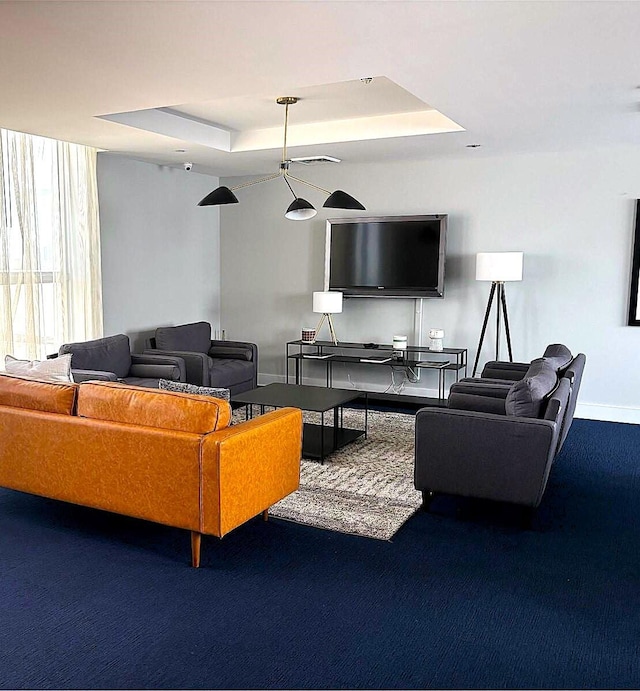 carpeted living area with a tray ceiling, visible vents, and baseboards