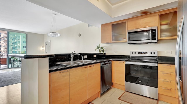 kitchen featuring a peninsula, light brown cabinets, stainless steel appliances, and a sink