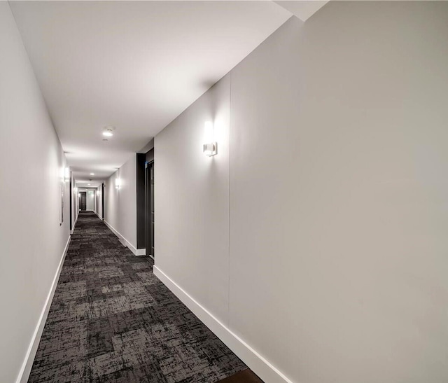 hall featuring baseboards and dark colored carpet