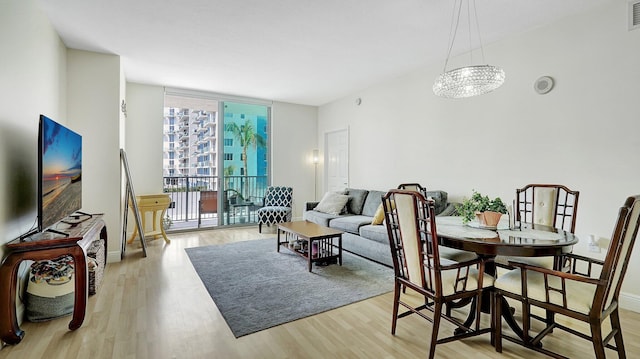 dining room featuring visible vents, light wood-style flooring, floor to ceiling windows, an inviting chandelier, and baseboards