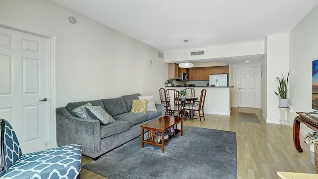 living area with light wood-type flooring, visible vents, and baseboards