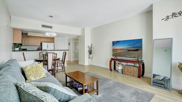 living area with visible vents, baseboards, and light wood-style flooring