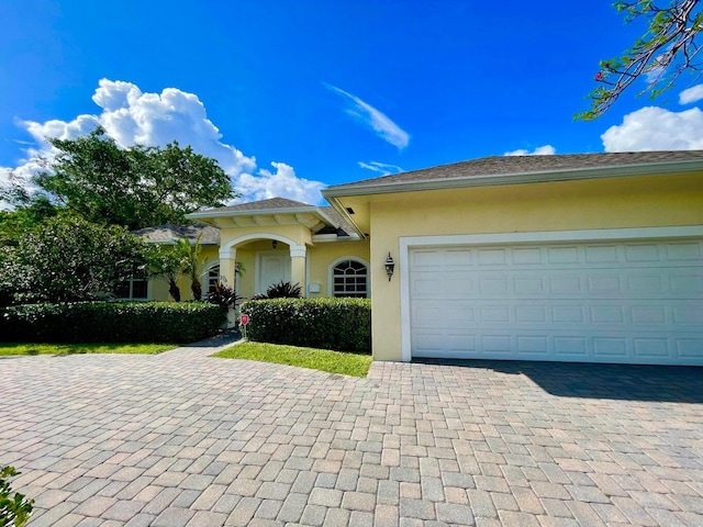 view of front of property featuring an attached garage, decorative driveway, and stucco siding