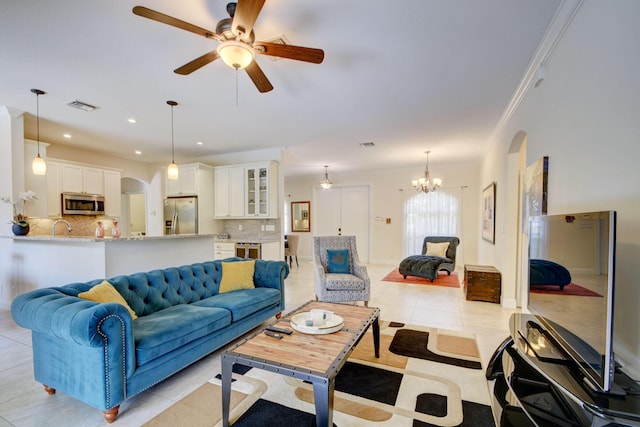 living area featuring arched walkways, light tile patterned flooring, recessed lighting, ceiling fan with notable chandelier, and visible vents